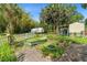 Lush backyard with palm trees, small sheds, a white picket fence, and tropical vegetation at 5635 Burts Park Rd, De Leon Springs, FL 32130