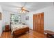 Cozy bedroom with ceiling fan, wood floors, natural light, and closet with louvered doors at 5635 Burts Park Rd, De Leon Springs, FL 32130