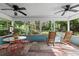 Spacious enclosed porch with ceiling fans, comfortable seating, and views of lush backyard at 5635 Burts Park Rd, De Leon Springs, FL 32130