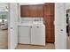 Convenient laundry room featuring a white washer and dryer with brown cabinets for storage at 600 N Boundary Ave # 118B, Deland, FL 32720