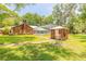 Spacious backyard with lush green grass, mature trees, pool enclosure, and a brick outbuilding at 712 S Timberlane Dr, New Smyrna Beach, FL 32168