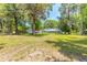 Backyard featuring a pool enclosure, mature trees, lush green grass, and space to roam at 712 S Timberlane Dr, New Smyrna Beach, FL 32168