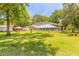 Lush backyard featuring a pool enclosure, brick outbuilding, and mature landscaping at 712 S Timberlane Dr, New Smyrna Beach, FL 32168