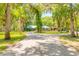 Scenic driveway approaching a brick house with a turquoise roof, amidst lush trees at 712 S Timberlane Dr, New Smyrna Beach, FL 32168