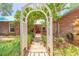 Charming home entrance showcasing a garden walkway with a white pergola and a red front door at 712 S Timberlane Dr, New Smyrna Beach, FL 32168