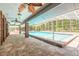 Covered patio by a screened-in pool features brick flooring and ceiling fans at 712 S Timberlane Dr, New Smyrna Beach, FL 32168