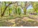 Lush green yard with mature trees leading to a cozy brick home and metal outbuilding at 712 S Timberlane Dr, New Smyrna Beach, FL 32168