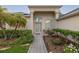 Close-up of front entry, showing glass door, landscaping, and seating area with plants on porch at 723 Oakwater Ln, Port Orange, FL 32128