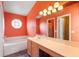 Well-lit bathroom with orange walls, a soaking tub, and a vanity with a large mirror at 809 Brightview Dr, Lake Mary, FL 32746
