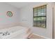 Modern bathroom features a large soaking tub, tiled floor, and a bright window at 901 Vicksburg St, Deltona, FL 32725