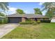 Charming brick home with a manicured lawn, lush landscaping, and attached two-car garage at 901 Vicksburg St, Deltona, FL 32725