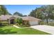 Beautifully landscaped brick home with lush greenery, a two-car garage, and a charming entryway at 980 Marjorie Rawlings Dr, Deland, FL 32720