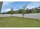 Spacious backyard featuring green lawn, white fence, and young trees, ideal for outdoor activities at 1002 River Falls Cir, Deland, FL 32720