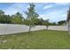 Large backyard featuring a green lawn, white fence, and young trees, offering privacy and outdoor space at 1002 River Falls Cir, Deland, FL 32720