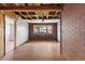 A living room with hardwood flooring, exposed beams, and a brick accent wall awaits renovation at 104 N Park Pl, Edgewater, FL 32132
