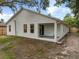 Exterior view of home's backyard with lush greenery, covered patio, and sliding glass doors at 1092 Gage Ave, Deltona, FL 32738