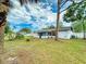 Backyard featuring the home's exterior, a storage shed, tropical trees, and a well-maintained lawn at 1229 Jeffery Dr, Port Orange, FL 32129