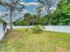 Spacious backyard featuring tropical plants, a fire pit, and a white privacy fence at 1229 Jeffery Dr, Port Orange, FL 32129