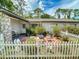 View of quaint outdoor patio with white picket fence, mature plants, outdoor seating, and stone statues at 1229 Jeffery Dr, Port Orange, FL 32129