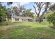 Charming exterior view of a well-maintained home with lush landscaping, featuring mature trees and a spacious yard at 1402 E Voorhis Ave, Deland, FL 32724