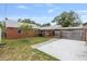 Fenced backyard with brick house, carport, patio and small trees at 1411 Cliff Ave, Eustis, FL 32726
