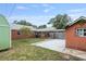 Fenced backyard with brick house, sheds, patio and small trees at 1411 Cliff Ave, Eustis, FL 32726