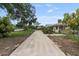 Long concrete driveway leading to a well-kept yellow home with mature landscaping and a brick chimney at 1411 Cliff Ave, Eustis, FL 32726