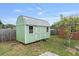 Green shed with white trim in a fenced backyard with small trees at 1411 Cliff Ave, Eustis, FL 32726