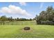 Fenced backyard with well-maintained lawn, trees, and a cozy fire pit, perfect for outdoor gatherings at 1444 Daystar Ln, Deltona, FL 32725