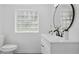 Bathroom featuring glass block window, modern vanity with round mirror, and updated toilet at 1518 Lakeside Dr, Deland, FL 32720