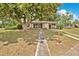 Charming single-story home with a walkway leading up to a covered porch, shaded by a large tree at 1610 Brady Dr, Deltona, FL 32725