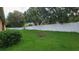 Lush green backyard with a white fence, partial view of neighborhood homes, and mature trees at 1632 Blue Grass Blvd, Deland, FL 32724
