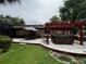 The brick home has a wooden deck with a hot tub and red pergola overlooking the lush backyard at 180 Pine Grove Ct, Daytona Beach, FL 32119