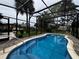 Relaxing kidney-shaped in-ground pool inside a screen-enclosed lanai and a beautifully landscaped backyard at 180 Pine Grove Ct, Daytona Beach, FL 32119