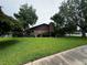 A well-manicured lawn surrounds this house, with its brick chimney, lush landscaping, and mature trees on an overcast day at 180 Pine Grove Ct, Daytona Beach, FL 32119