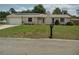 Charming single-story home featuring an attached garage, solar panels, and a well-maintained lawn at 1821 Talmadge St, Deland, FL 32724