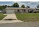 Charming single-story home featuring an attached garage, solar panels, and a well-maintained lawn at 1821 Talmadge St, Deland, FL 32724