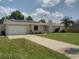 Charming single-story home featuring an attached garage, solar panels, and a well-maintained lawn at 1821 Talmadge St, Deland, FL 32724