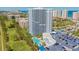 Stunning aerial view of a high-rise condo, golf course, swimming pool, parking, and beach access at 2 Oceans West Blvd # 305, Daytona Beach, FL 32118