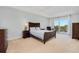Bright main bedroom with a ceiling fan, balcony access, and wood furniture at 2 Oceans West Blvd # 305, Daytona Beach, FL 32118