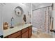 Well-lit bathroom has a decorative vanity, and a shower with a charming floral curtain at 2412 Regency Park Dr, Deland, FL 32724