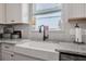 Close-up of a farmhouse sink with white cabinets and granite countertops in the kitchen at 2412 Regency Park Dr, Deland, FL 32724