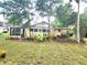 Exterior view of home featuring a modest lawn, mature trees, and a small screened porch area at 2647 Brookline Ave, New Smyrna Beach, FL 32168