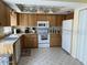 Bright kitchen with wood cabinetry, white appliances, and ample counter space at 2898 Ocean Shore Blvd # 603, Ormond Beach, FL 32176