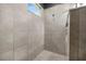 Walk-in shower featuring neutral tiling, a small window, and a convenient hand-held shower attachment at 2948 Bella Flore Ter, New Smyrna Beach, FL 32168