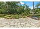 Serene backyard retreat featuring a stone patio, lush landscaping, and a tranquil seating area at 3592 Grande Tuscany Way, New Smyrna Beach, FL 32168