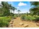 Scenic backyard view with a decorative stone pathway, tranquil landscaping, and distant water feature at 3592 Grande Tuscany Way, New Smyrna Beach, FL 32168