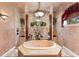 Luxurious bathroom featuring a standalone soaking tub, chandelier, and elegant tile work at 3592 Grande Tuscany Way, New Smyrna Beach, FL 32168