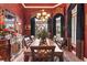 Elegant dining room with a large table set for a formal meal, featuring rich red walls and sophisticated decor at 3592 Grande Tuscany Way, New Smyrna Beach, FL 32168