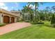 Beautiful home exterior with a brick driveway, well-manicured lawn, and charming landscaping at 3592 Grande Tuscany Way, New Smyrna Beach, FL 32168